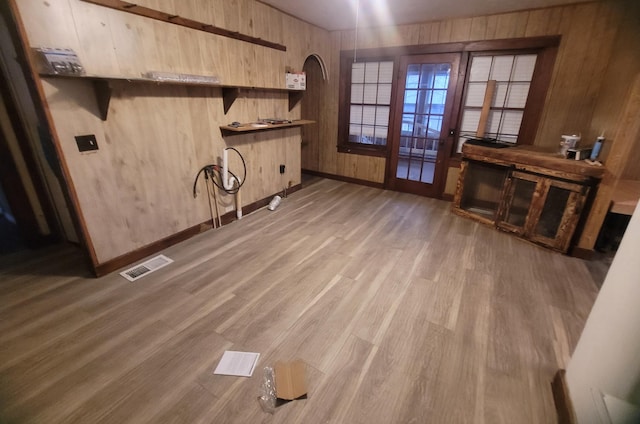 laundry area with hardwood / wood-style floors, wooden walls, and french doors