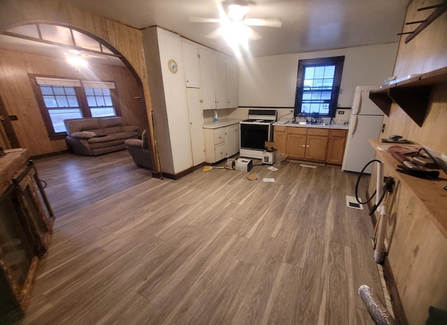 office space with wooden walls, sink, ceiling fan, and light wood-type flooring