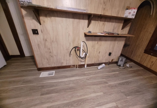 laundry room featuring wood-type flooring and wooden walls