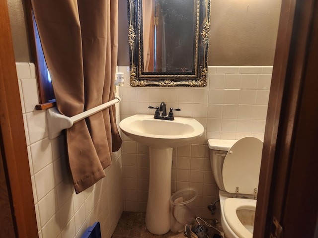 bathroom with tile patterned flooring, tile walls, and toilet