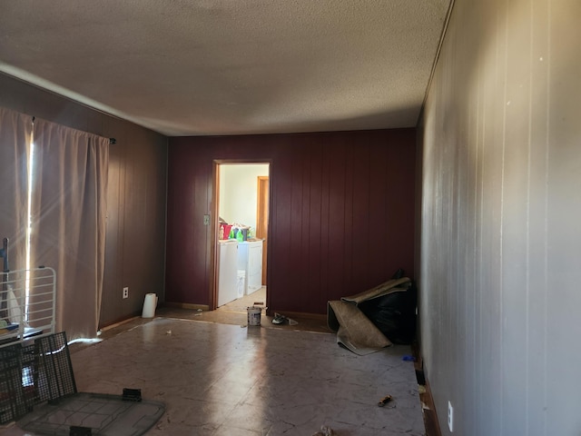 empty room featuring wooden walls, washing machine and dryer, and a textured ceiling