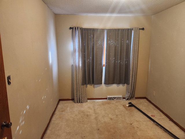 empty room featuring light carpet and a textured ceiling