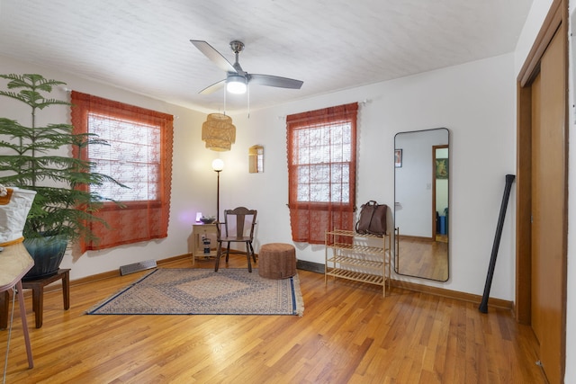 living area featuring light wood-type flooring and ceiling fan