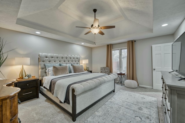 carpeted bedroom featuring a raised ceiling and ceiling fan