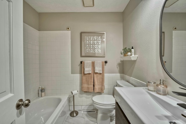 full bathroom with a textured ceiling, toilet, shower / washtub combination, vanity, and tile walls