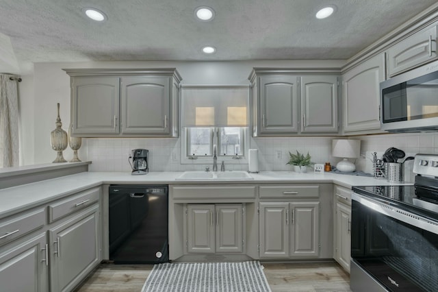 kitchen featuring appliances with stainless steel finishes, light wood-type flooring, gray cabinets, and sink