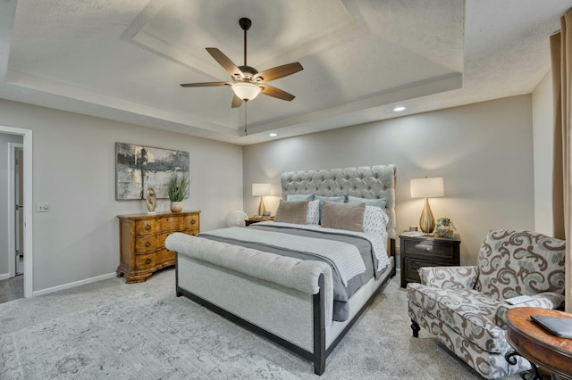 bedroom featuring light carpet, a raised ceiling, and ceiling fan