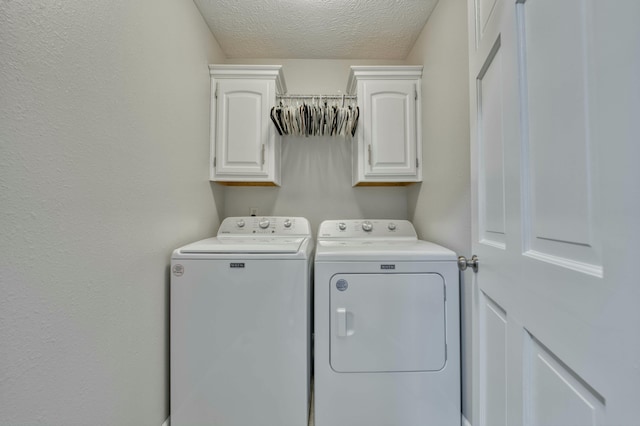 laundry area with cabinets, a textured ceiling, and separate washer and dryer