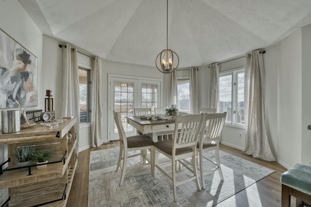 dining room featuring plenty of natural light, a chandelier, vaulted ceiling, and light wood-type flooring