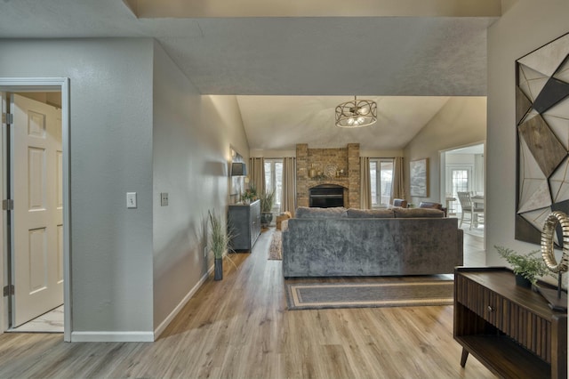 living room featuring light hardwood / wood-style floors, lofted ceiling, a fireplace, and a chandelier