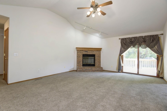 unfurnished living room with a fireplace, lofted ceiling, rail lighting, and light carpet