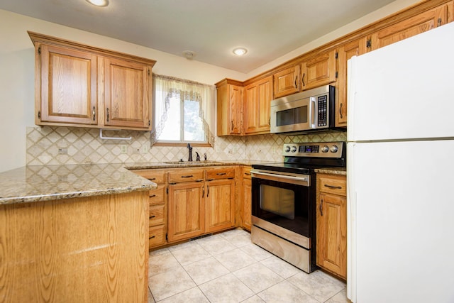 kitchen with backsplash, sink, appliances with stainless steel finishes, light tile patterned flooring, and kitchen peninsula