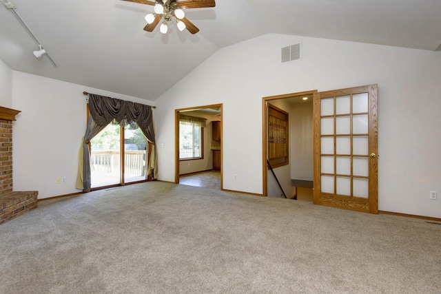 unfurnished living room with ceiling fan, rail lighting, light colored carpet, and lofted ceiling