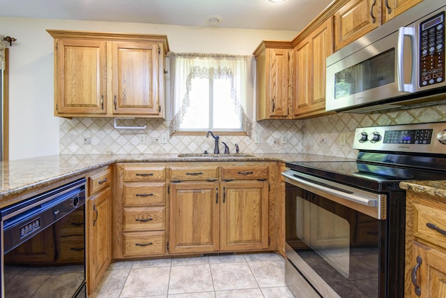 kitchen with sink, light stone counters, backsplash, light tile patterned flooring, and appliances with stainless steel finishes