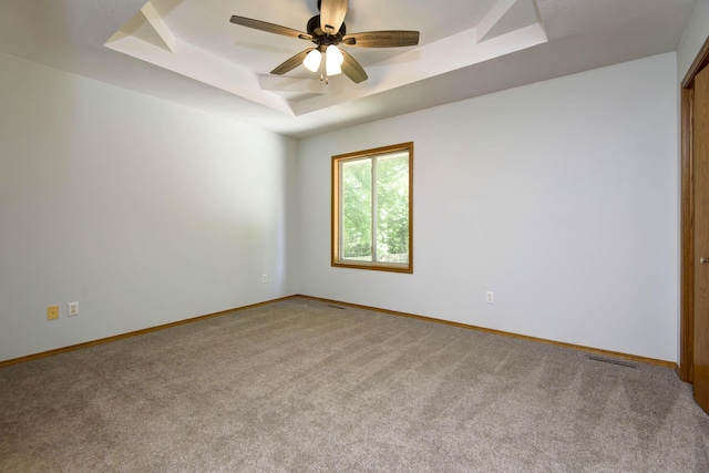 carpeted spare room featuring ceiling fan and a tray ceiling