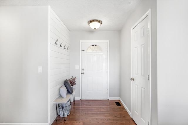 doorway with a textured ceiling and dark wood-type flooring