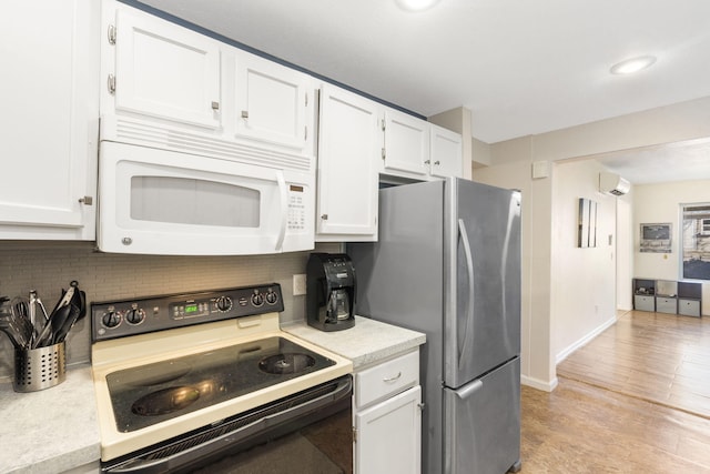 kitchen featuring a wall mounted air conditioner, backsplash, electric stove, white cabinets, and stainless steel refrigerator