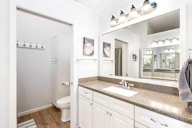 bathroom with wood-type flooring, vanity, toilet, and ornamental molding