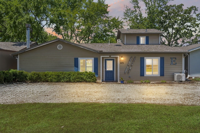 view of front of property featuring ac unit and a lawn