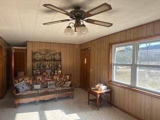 unfurnished living room with light colored carpet, ceiling fan, and wood walls