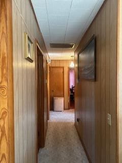 hall with light carpet and wooden walls