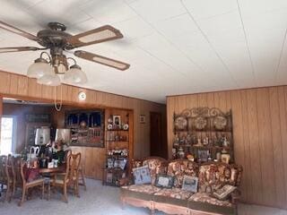 living room featuring wood walls and ceiling fan