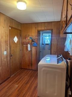 laundry area with hardwood / wood-style floors, washer / clothes dryer, and wooden walls