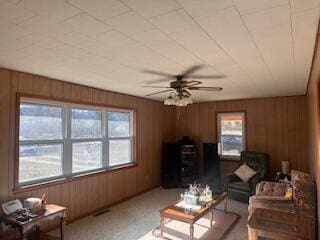 living room featuring ceiling fan and wooden walls