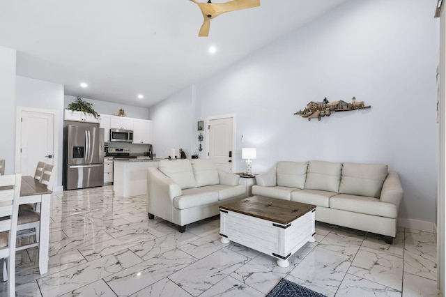 living area with a towering ceiling, marble finish floor, baseboards, and recessed lighting