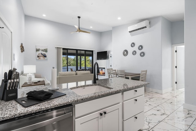 kitchen with a sink, white cabinetry, open floor plan, stainless steel dishwasher, and a wall mounted AC
