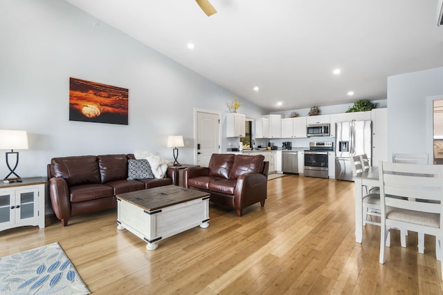 living room with light wood-style floors, recessed lighting, and high vaulted ceiling