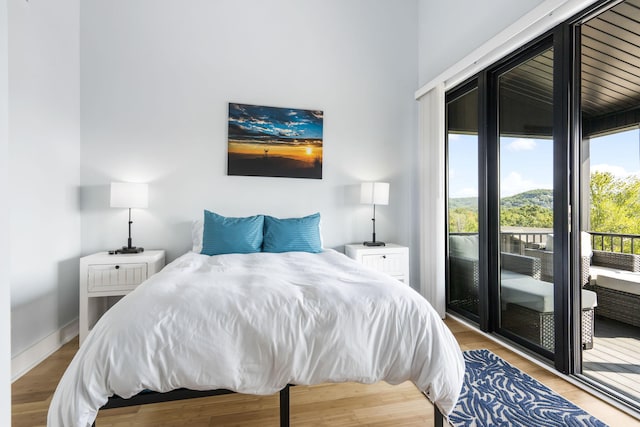 bedroom featuring access to exterior, baseboards, and wood finished floors