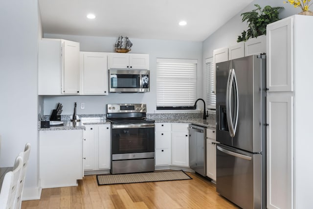 kitchen with appliances with stainless steel finishes, white cabinets, and light stone countertops