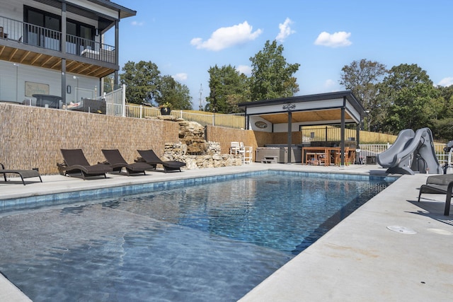 view of swimming pool with a patio, a water slide, fence, outdoor dry bar, and a fenced in pool