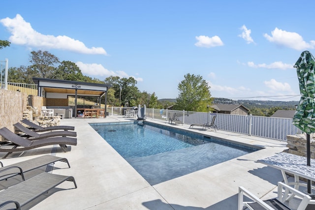 view of swimming pool with outdoor dry bar, a patio, fence, and a fenced in pool