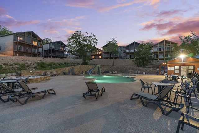 community pool with a water slide and a patio area
