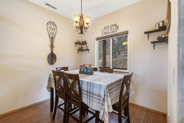 dining room with dark hardwood / wood-style flooring and an inviting chandelier