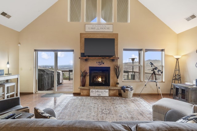 living room with a towering ceiling, a healthy amount of sunlight, and hardwood / wood-style flooring