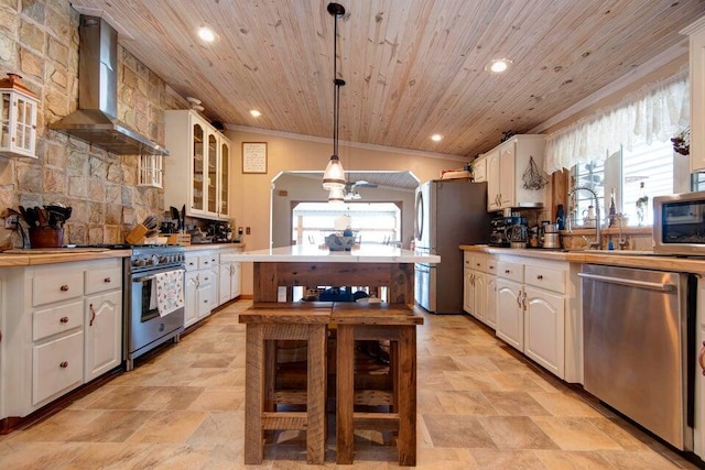 kitchen featuring pendant lighting, white cabinets, stainless steel appliances, wooden ceiling, and wall chimney exhaust hood