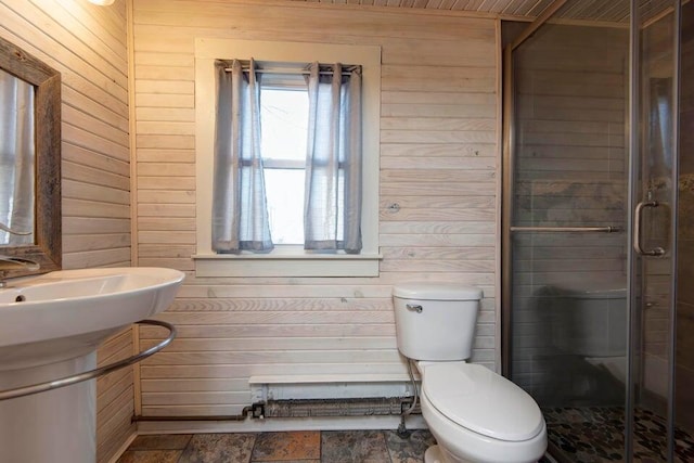 bathroom featuring a shower with shower door, toilet, and wood walls