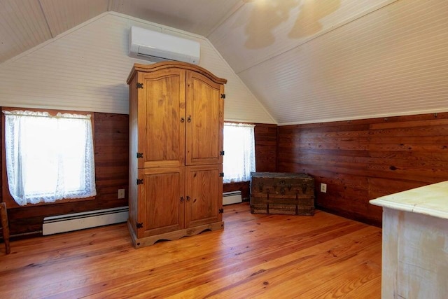 additional living space with vaulted ceiling, a wall unit AC, light hardwood / wood-style floors, and baseboard heating