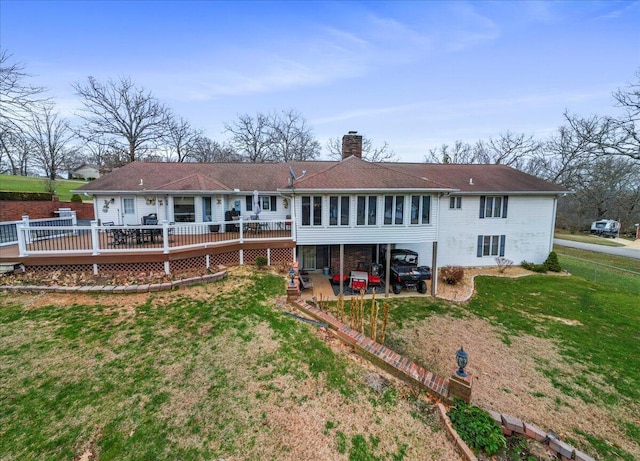 rear view of house featuring a lawn and a deck