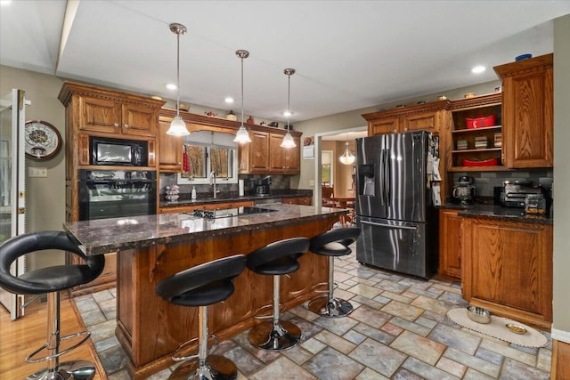 kitchen featuring black appliances, backsplash, a center island, and hanging light fixtures