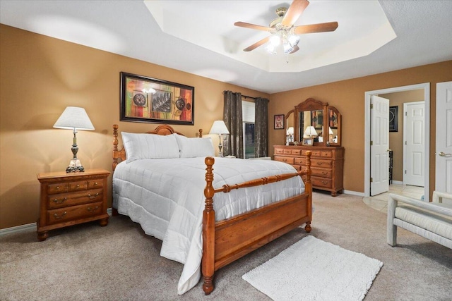 carpeted bedroom featuring a raised ceiling and ceiling fan