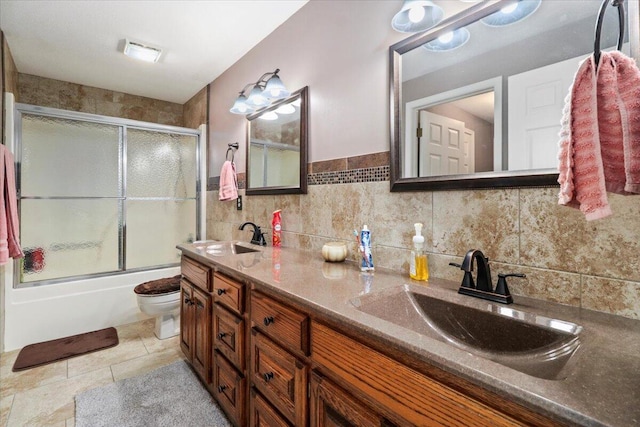 full bathroom with combined bath / shower with glass door, vanity, toilet, and tile walls