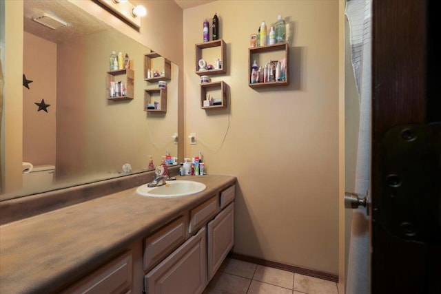 bathroom with toilet, vanity, and tile patterned floors