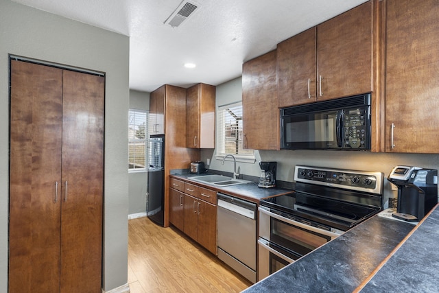 kitchen with black appliances, light wood-type flooring, and sink