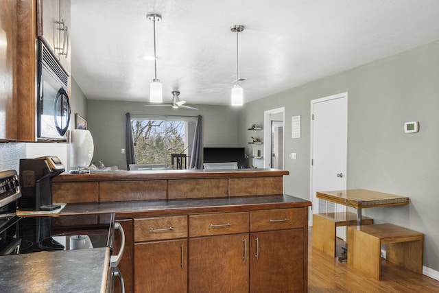 kitchen with ceiling fan, stainless steel range, light hardwood / wood-style floors, and decorative light fixtures