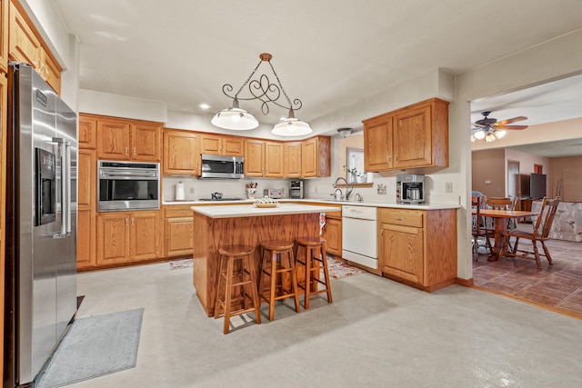 kitchen featuring sink, stainless steel appliances, decorative light fixtures, a kitchen bar, and a kitchen island