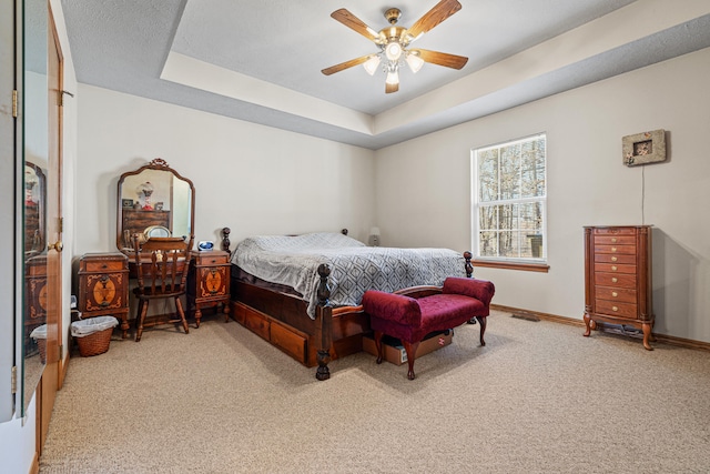 carpeted bedroom with a tray ceiling and ceiling fan